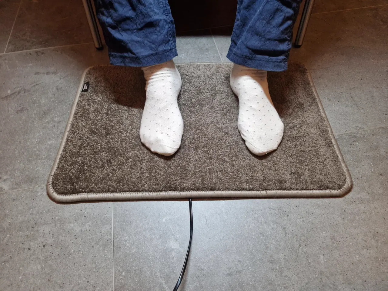 Warme voeten in sokken op de taupe elektrische voetenmat Excellent, handgemaakt in Nederland